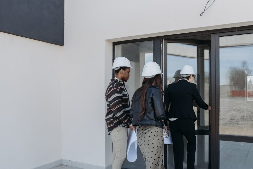 A group of diverse clients with a realtor at a new construction site entrance.
